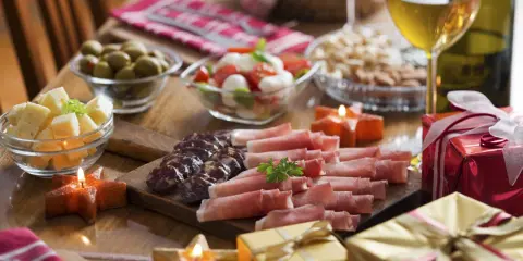 Eleganckie menu na sylwestra w domu: wędliny, sery, oliwki, pomidorki z mozzarellą, orzechy, wino i prezenty.