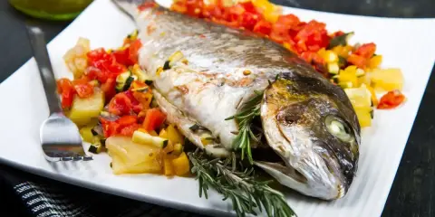 Orata intera cotta in friggitrice ad aria, servita con verdure miste e rosmarino.