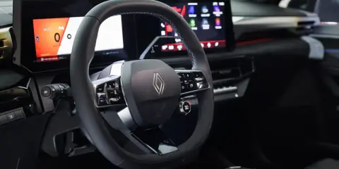 Volante e cruscotto digitale con schermi moderni, dettagli blu e logo Renault. Interni della nuova Clio 2026.
