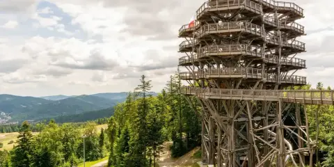 Wieża widokowa w Krynicy Zdroju, otoczona zielonymi górami, zaprasza do podziwiania panoramy Beskidu Sądeckiego.
