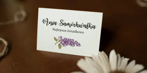 Winietka z napisem "Ania Samochwałka Najlepsza świadkowa" i gałązką bzu. Idealna inspiracja, jak wypisać winietki dla rodziców.
