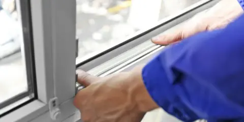 Manos ajustando el burlete para aislar ventanas, mejorando la eficiencia energética del hogar.