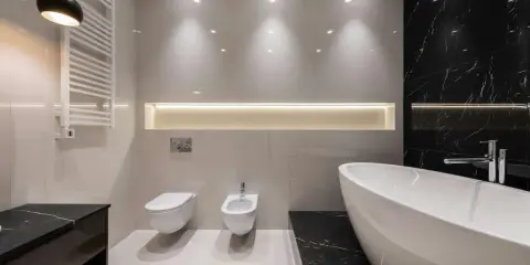 Radiador toallero blanco colgado en pared junto a un inodoro y bidet, ideal para baños modernos.
