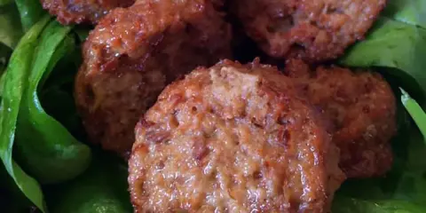 Polpette di lenticchie dorate e croccanti su un letto di spinaci freschi.