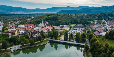 Malownicze miasteczko w Chorwacji, otoczone zielonymi wzgórzami i górami. Jezioro odbija kolorowe dachy domów.