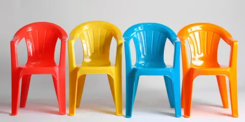 Cztery kolorowe krzesła: czerwone, żółte, niebieskie i pomarańczowe. Idealne na zewnątrz, jaka farba do plastiku na zewnątrz sprawdzi się najlepiej?