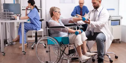Rehabilitacja po udarze w szpitalu: starsza pani ćwiczy z fizjoterapeutą, by odzyskać sprawność.