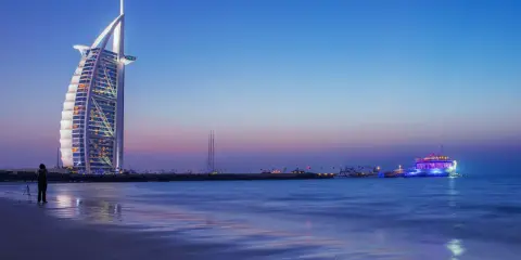 Wieżowiec Burdż al-Arab i plaża w Dubaju o zmierzchu.