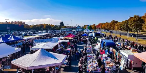 Buntes Treiben auf dem flohmarkt paderborn. Viele Stände mit Kleidung und Trödel unter blauem Himmel.