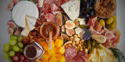 Plateau charcuterie et fromages : un buffet généreux avec jambon, saucisson, fromages variés, fruits, noix et confitures.