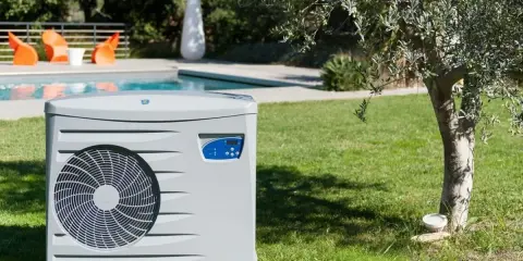 Pompe à chaleur pour piscine, élément clé d'un schéma de filtration performant, installée sur une pelouse verdoyante près d'une piscine.