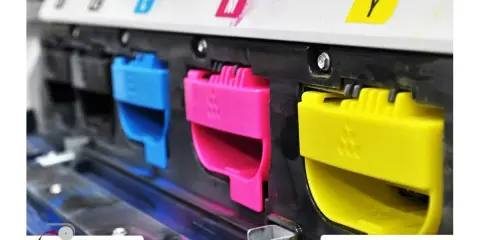 Kolorowe wkłady drukujące (cyjan, magenta, żółty) w drukarce, symbolizujące nowoczesne technologie druku.