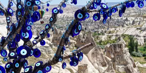 Ein Baum voller blauer Glasaugen, die wie ein arabisches Auge vor der Felslandschaft von Kappadokien schützen.