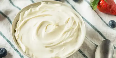 Un bol de crème mascarpone onctueuse, garni de fraises et de myrtilles, prêt à être dégusté.