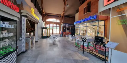 Wnętrze z neonami "Muzeum" i "Spółdzielczy dom handlowy". Atrakcje w Zamku Topacz to m.in. sklepiki i kawiarnia.