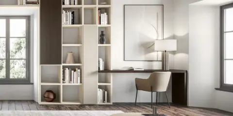 Un angolo studio ricavato in soggiorno, con libreria componibile, scrivania integrata e poltroncina.