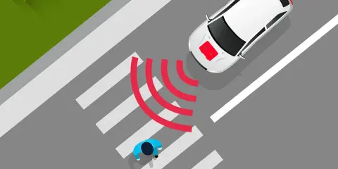 Coche eléctrico blanco se acerca a un paso de peatones. El sonido de los coches eléctricos es casi inaudible, pero las ondas rojas indican que detecta a los peatones.