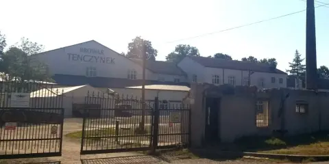 Brama wjazdowa do Browaru Tenczynek. W tle budynki browaru i wysoki komin.
