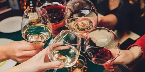 Ludzie wznoszą toasty winem. Pamiętaj o odpowiedzialnym spożywaniu alkoholu, zwłaszcza gdy rozważasz antykoncepcję.