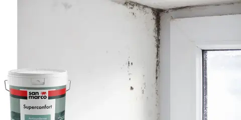 Angolo di una stanza con muffa sul muro e sul soffitto, accanto a un barattolo di vernice antimuffa San Marco Superconfort Anticondensa.