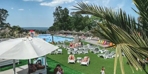 Solig dag vid poolen, perfekt för en semester i Sverige med barn. Folk solar, badar och njuter av värmen.