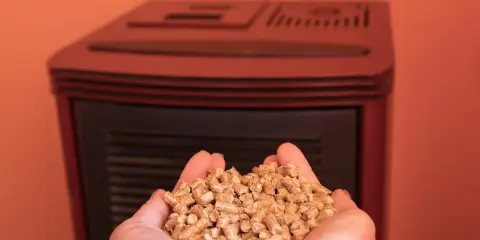Manos sostienen un puñado de pellets, combustible ecológico para estufas.