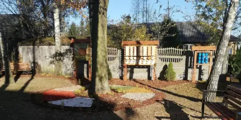 Ogród sensoryczny z ławkami, domkami dla owadów i kolorowymi nawierzchniami.