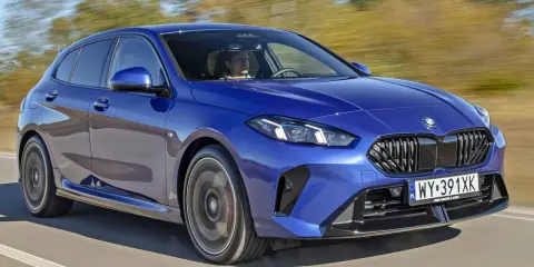Niebieskie BMW serii 1 (f21) w ruchu, z kierowcą za kierownicą.