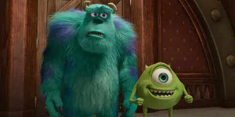 Sully i Mike, bohaterowie bajek z 4 postaciami, stoją obok siebie. Sully wygląda na zmartwionego, a Mike uśmiecha się szeroko.
