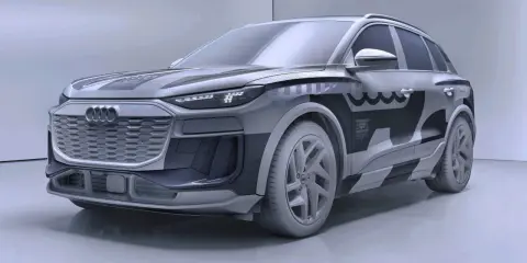 Przyszłościowy Audi Q6 e-tron w szarym kamuflażu, z charakterystycznym grillem i nowoczesnymi światłami LED.
