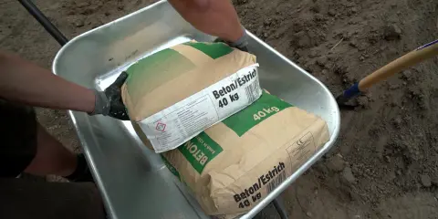 Zwei Säcke Beton/Estrich 40 kg liegen in einer Schubkarre. Verschiedene Estrich Arten sind für Bauprojekte wichtig.
