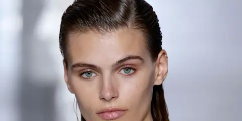 Ein Model mit glänzenden, nassen Haaren im Wet-Look-Stil, das einen intensiven Blick in die Kamera wirft.