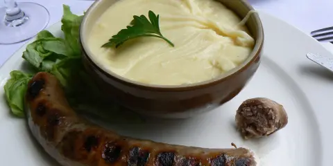 Saucisse grillée et purée onctueuse, un plat traditionnel auvergnat réconfortant.