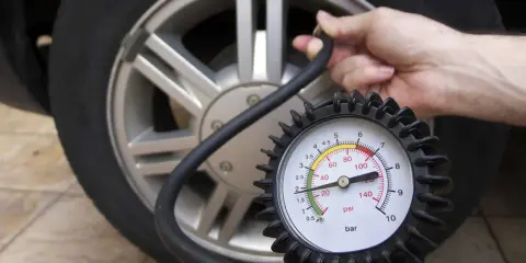 Controllo della pressione delle gomme auto con manometro. La lancetta indica circa 2 bar.