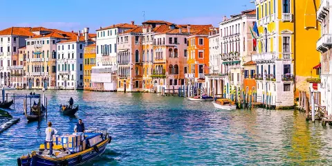 Gondole e vaporetti sul Canal Grande, un assaggio di cosa vedere a Venezia in due giorni. Palazzi colorati e acqua scintillante.