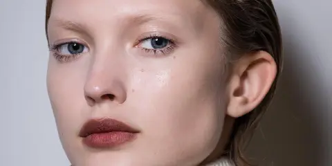 Primer plano de un rostro cuadrado con ojos azules y labios oscuros.