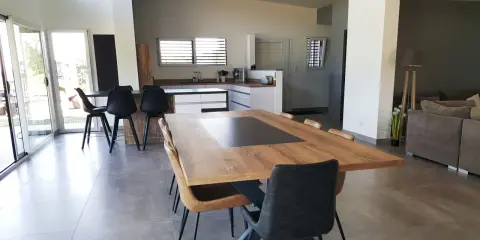 Grande cuisine ouverte sur salon, avec îlot central, table en bois et chaises modernes.