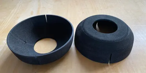 Zwei schwarze EPP-Platten, geformt wie Trichter und Zylinder, liegen auf einer Holzoberfläche.