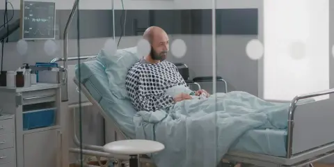 Mężczyzna w szpitalnym łóżku, z tlenem w nosie, czeka na wypis. Jego pobyt w szpitalu a zwolnienie lekarskie to teraz kluczowe kwestie.