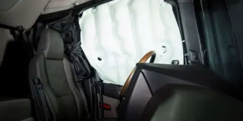 Nadmuchane kurtyny powietrzne w samochodzie chronią pasażerów. Widać fotel kierowcy i fragment kierownicy.