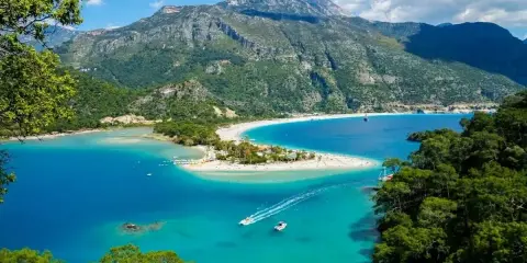 Malownicza zatoka z turkusową wodą i piaszczystą plażą, otoczona zielonymi wzgórzami. Idealne miejsce dla turystów szukających rajskich zakątków w turcja miasta turystyczne.
