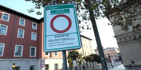 Señal de etiqueta medioambiental en Zaragoza, indicando zona de bajas emisiones con excepciones para carga, descarga, taxis, bicicletas y residentes.