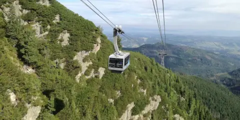 Kolejka linowa wjeżdża na zbocze porośnięte kosodrzewiną, oferując widok z Kasprowego na Giewont.