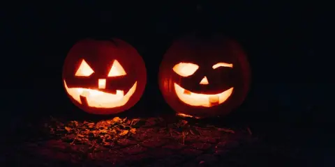 Två lysande pumpor med läskiga ansikten lyser upp mörkret. En perfekt syn för en halloween dag.