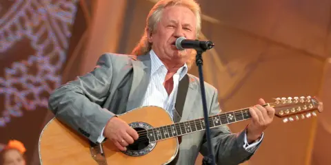 Artysta w szarym garniturze gra na gitarze i śpiewa. Kto śpiewał kolorowe jarmarki?