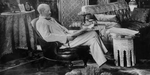 A man reads in a plush armchair, a dog sleeps nearby. The opulent room hints at the grandeur of the Rothschild art collection.