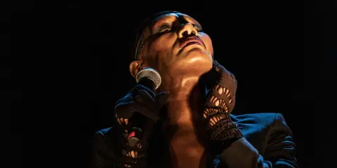 Grace Jones idag, med mikrofonen i handen och blicken uppåt, utstrålar ikonisk scenenergi.