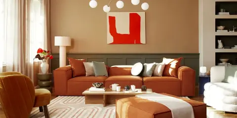 Salon chaleureux avec canapé orange, fauteuil assorti et tapis graphique. Un excellent conseil couleur peinture pour une ambiance cosy.