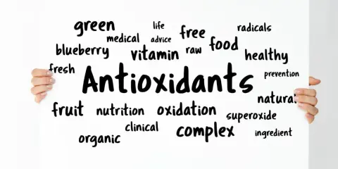 Tablica z napisem "Antioxidants" otoczona słowami kluczowymi, takimi jak "free radicals", "healthy food", "vitamin", "fruit", "blueberry".