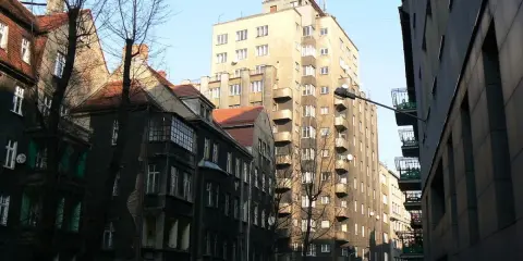 Wysoki, jasny drapacz chmur w Katowicach góruje nad starą kamienicą.
